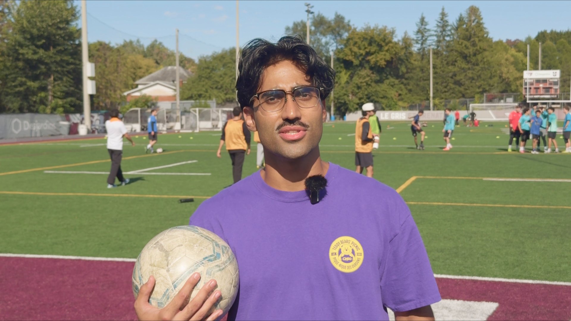 Finished colour grade: a presenter on a sunny soccer field, with richer greens and balanced contrast.